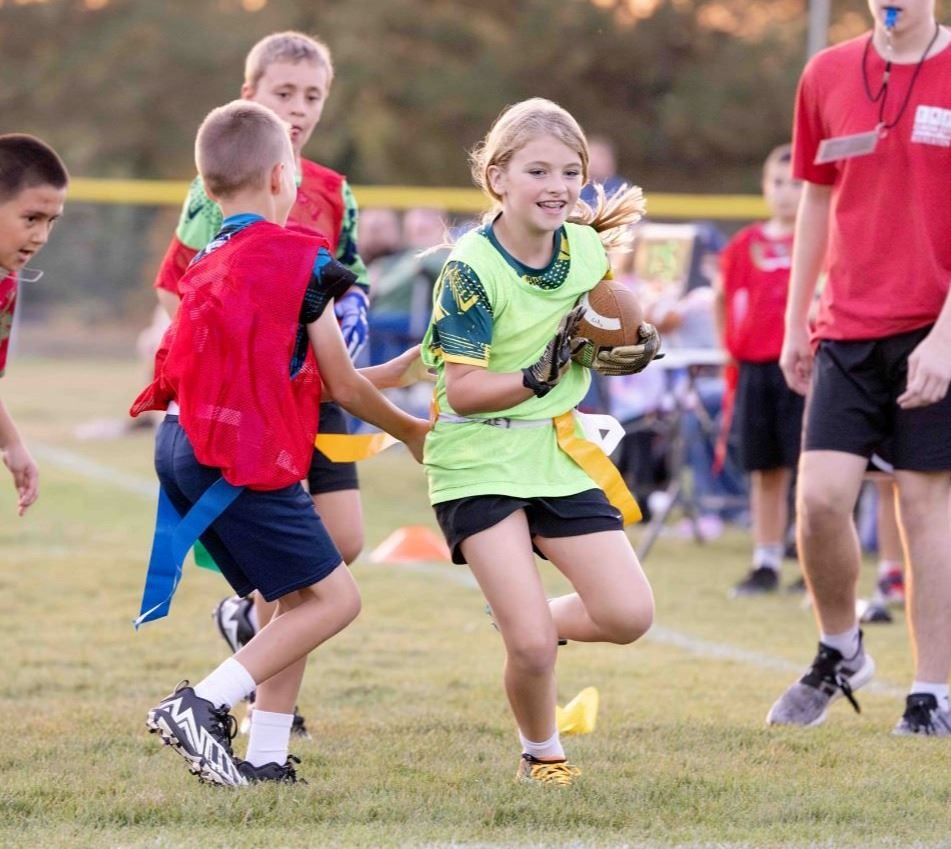 A flag football player running with a football
